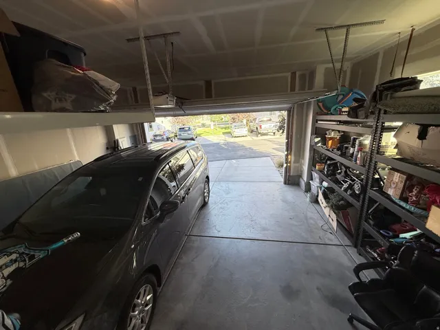 Attached garage featuring a concrete floor, exposed ceiling joists, and built-in overhead storage racks