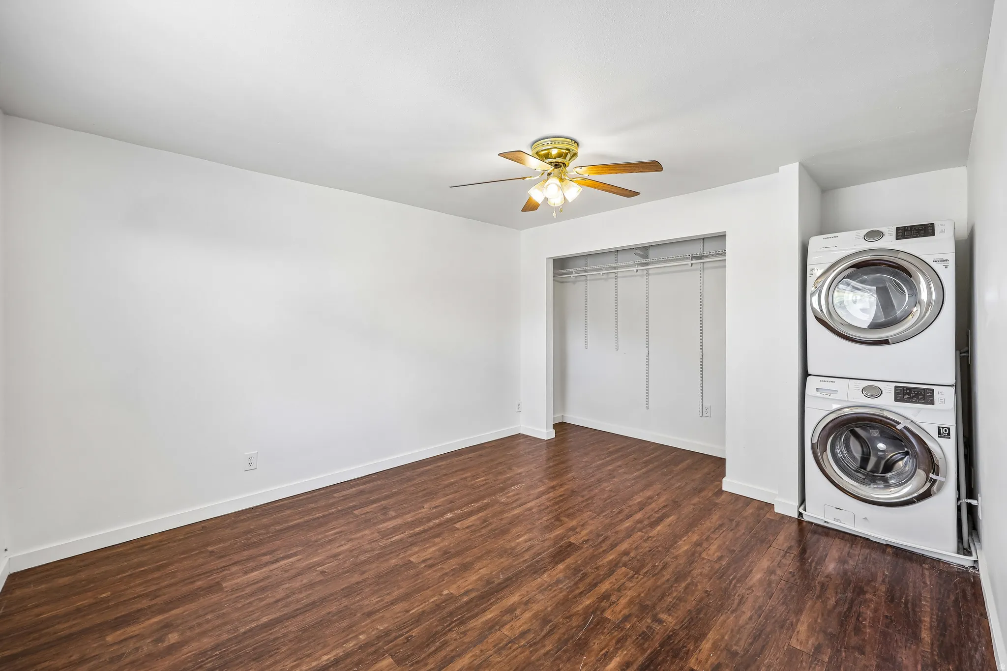 Room featuring wood-finish flooring, white walls, and a ceiling fan with light fixture