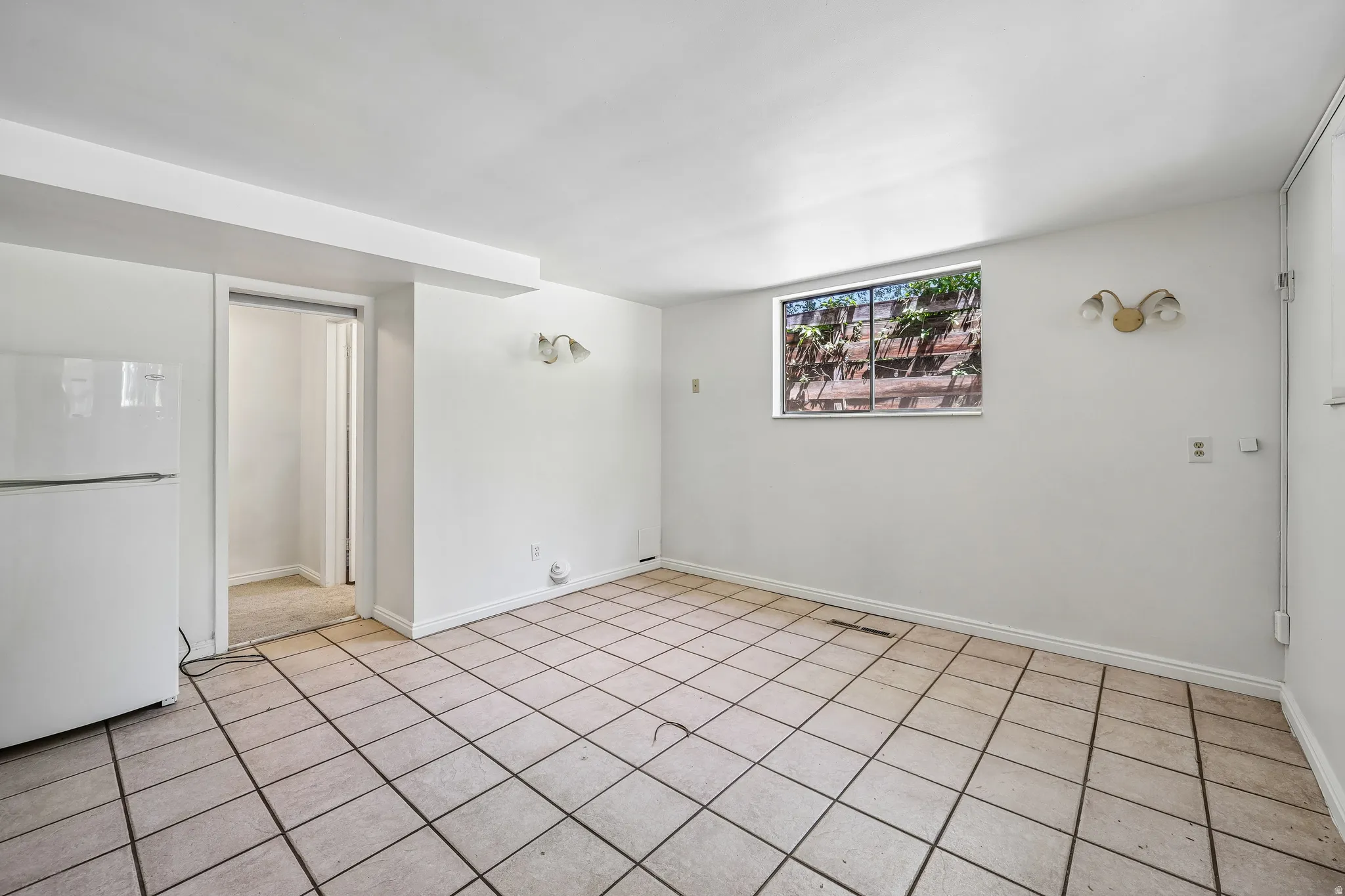 Spacious room featuring neutral tile flooring and a white color palette