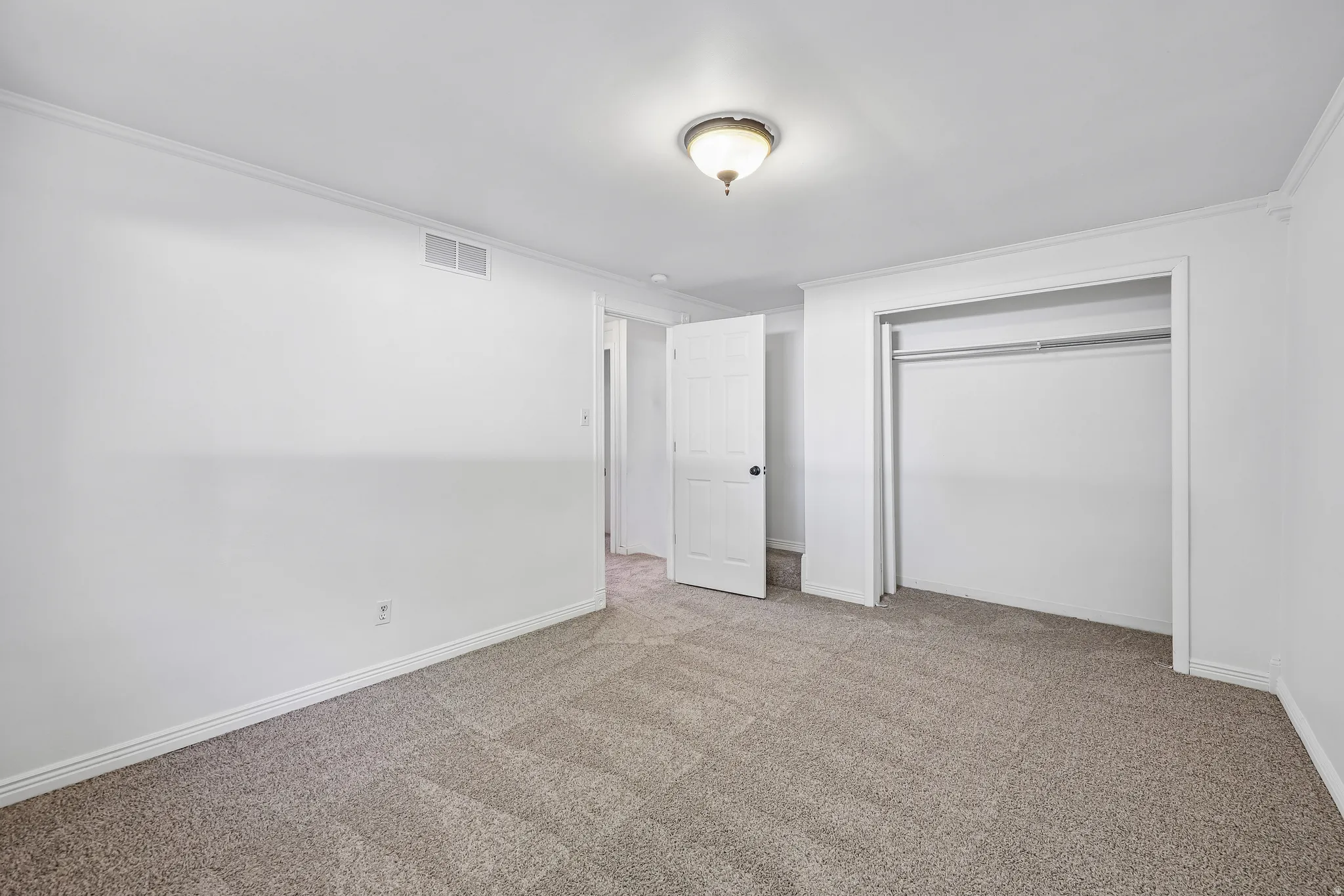 Carpeted room featuring a built-in closet with hanging rod, a white interior door, white baseboards, and a semi-flush mount ceiling light fixture