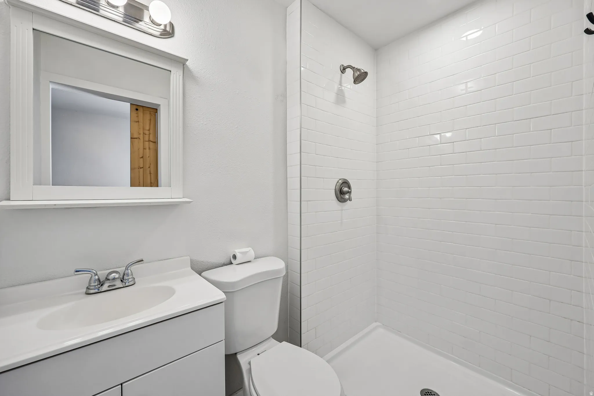 Bathroom featuring a white vanity with integrated sink, chrome faucet, and framed mirror with overhead lighting