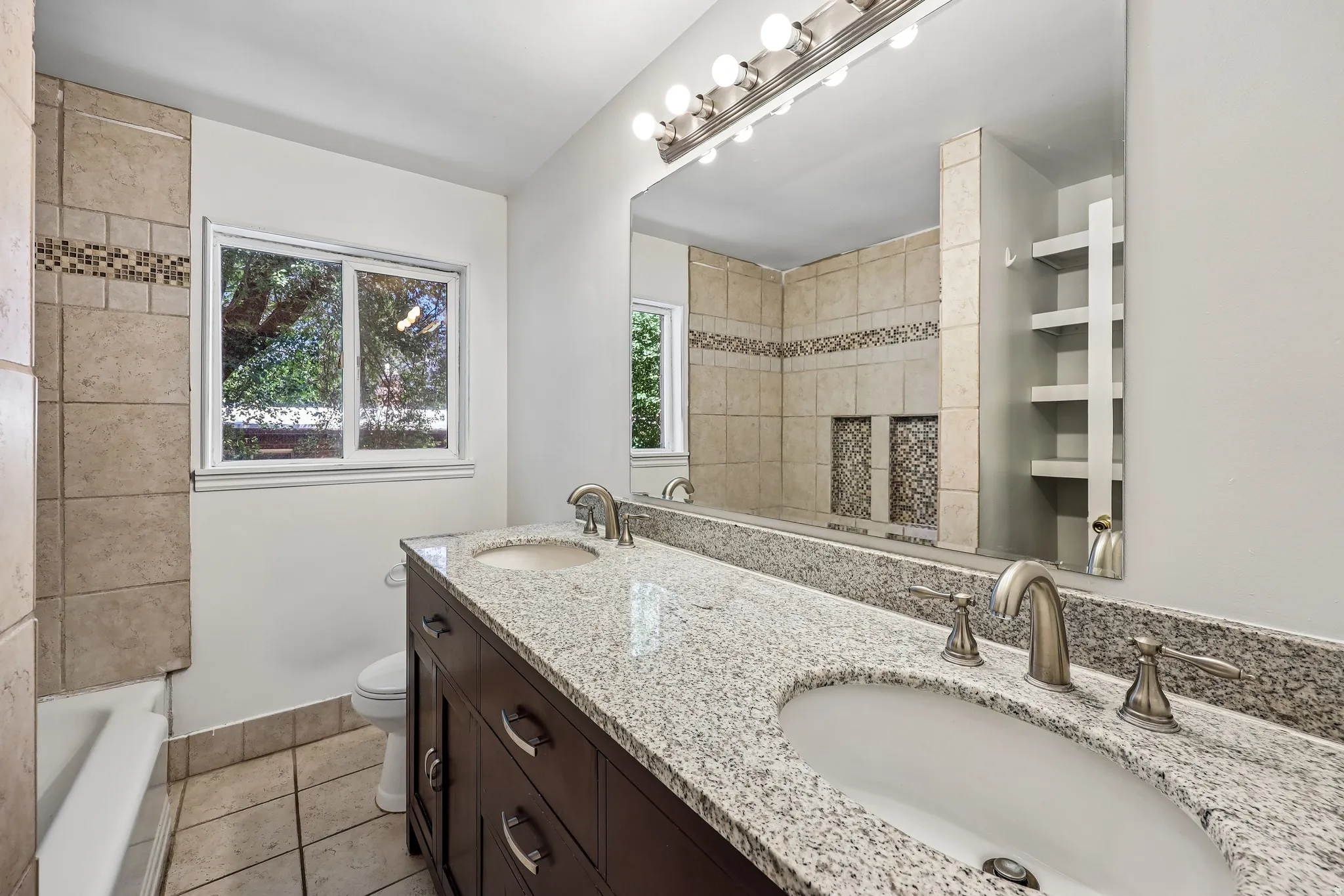 Bathroom featuring a dual vanity with granite countertop, undermount sinks, and brushed nickel fixtures