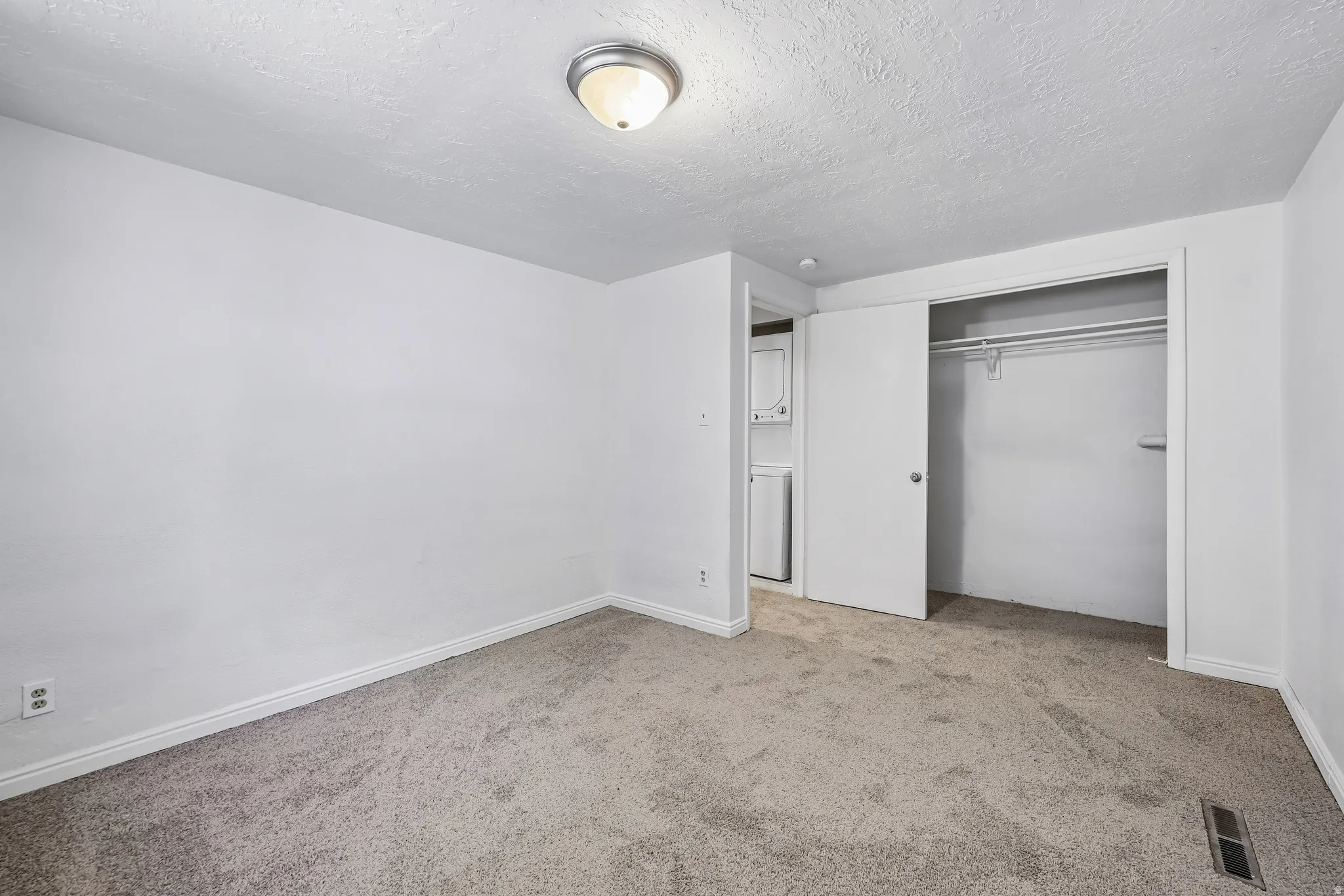 Carpeted room with white walls, a flush-mount ceiling light, and a built-in closet with sliding doors