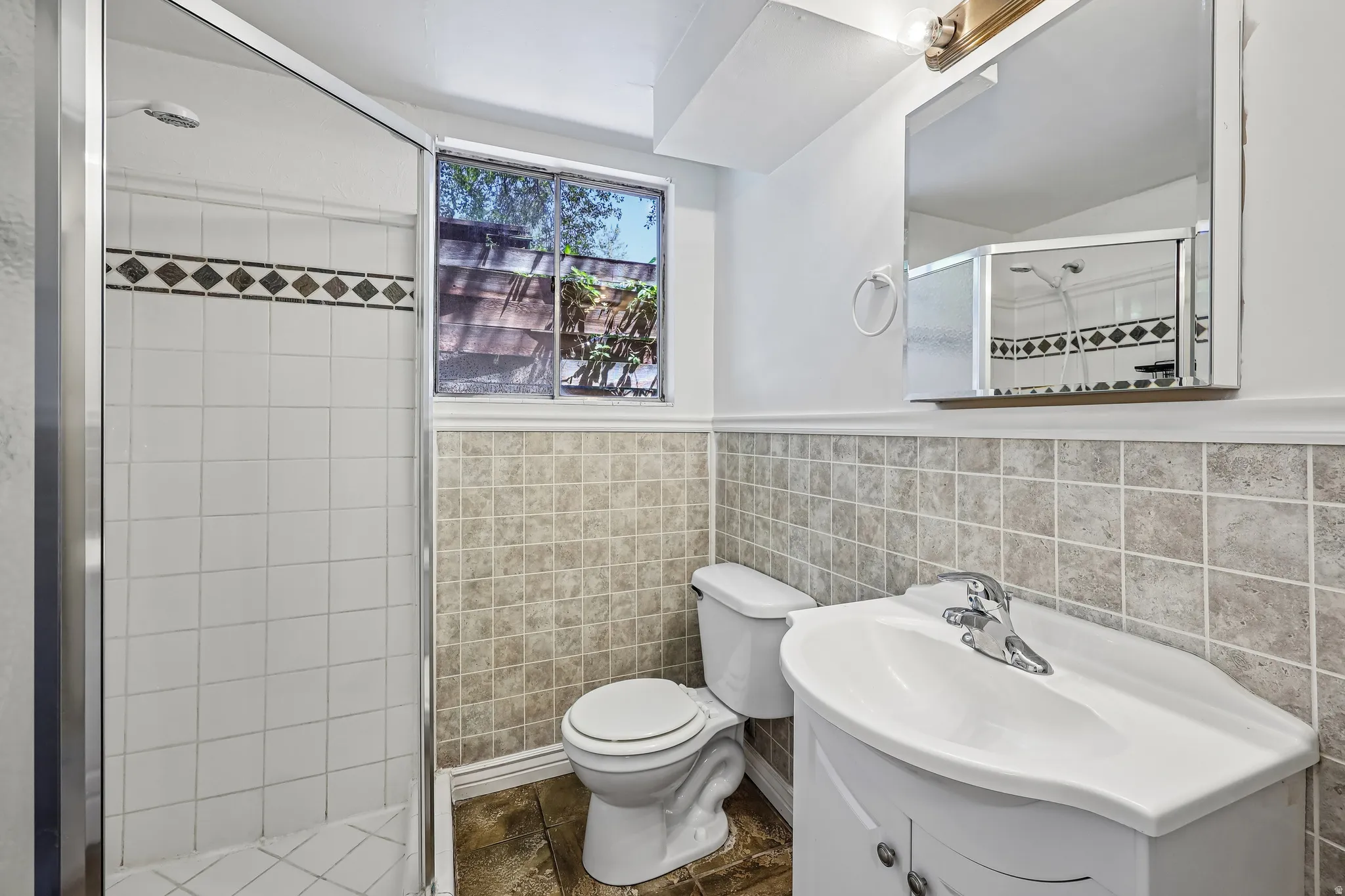 Bathroom featuring a shower with sliding glass doors and white tile surround, accented with a decorative tile border