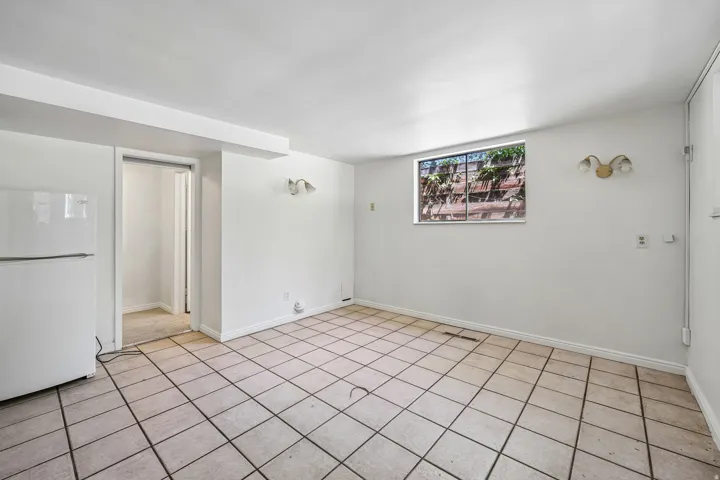 Spacious room featuring neutral tile flooring and a white color palette