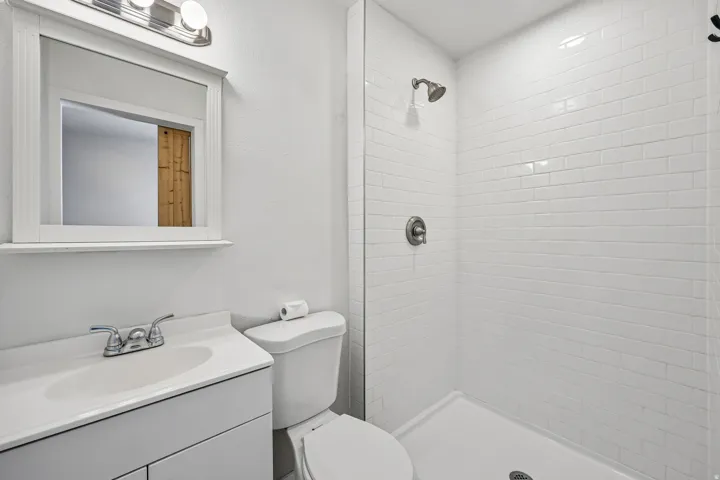 Bathroom featuring a white vanity with integrated sink, chrome faucet, and framed mirror with overhead lighting