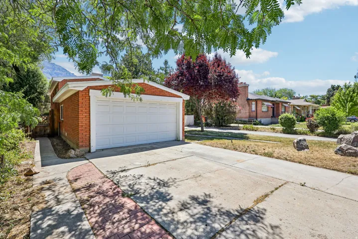 Brick exterior featuring an attached two-car garage with a white panel door, concrete driveway, and a red brick pathway