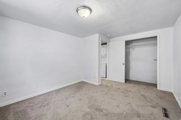 Carpeted room with white walls, a flush-mount ceiling light, and a built-in closet with sliding doors