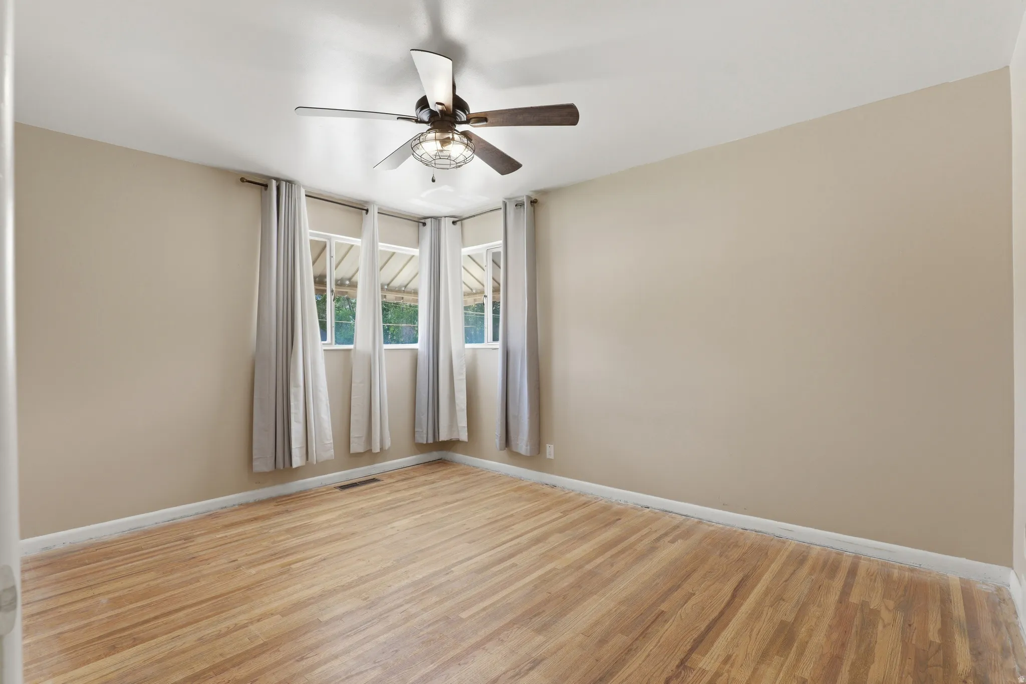 Hardwood-style flooring throughout this room, featuring light beige walls and a ceiling fan with integrated lighting