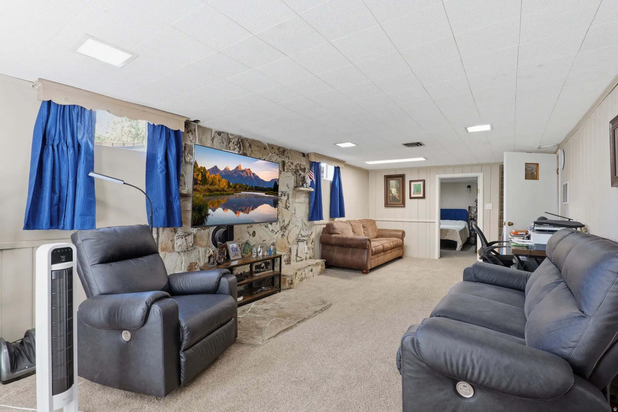 Spacious carpeted room featuring a stone-clad accent wall, recessed ceiling lighting, and beadboard wall paneling