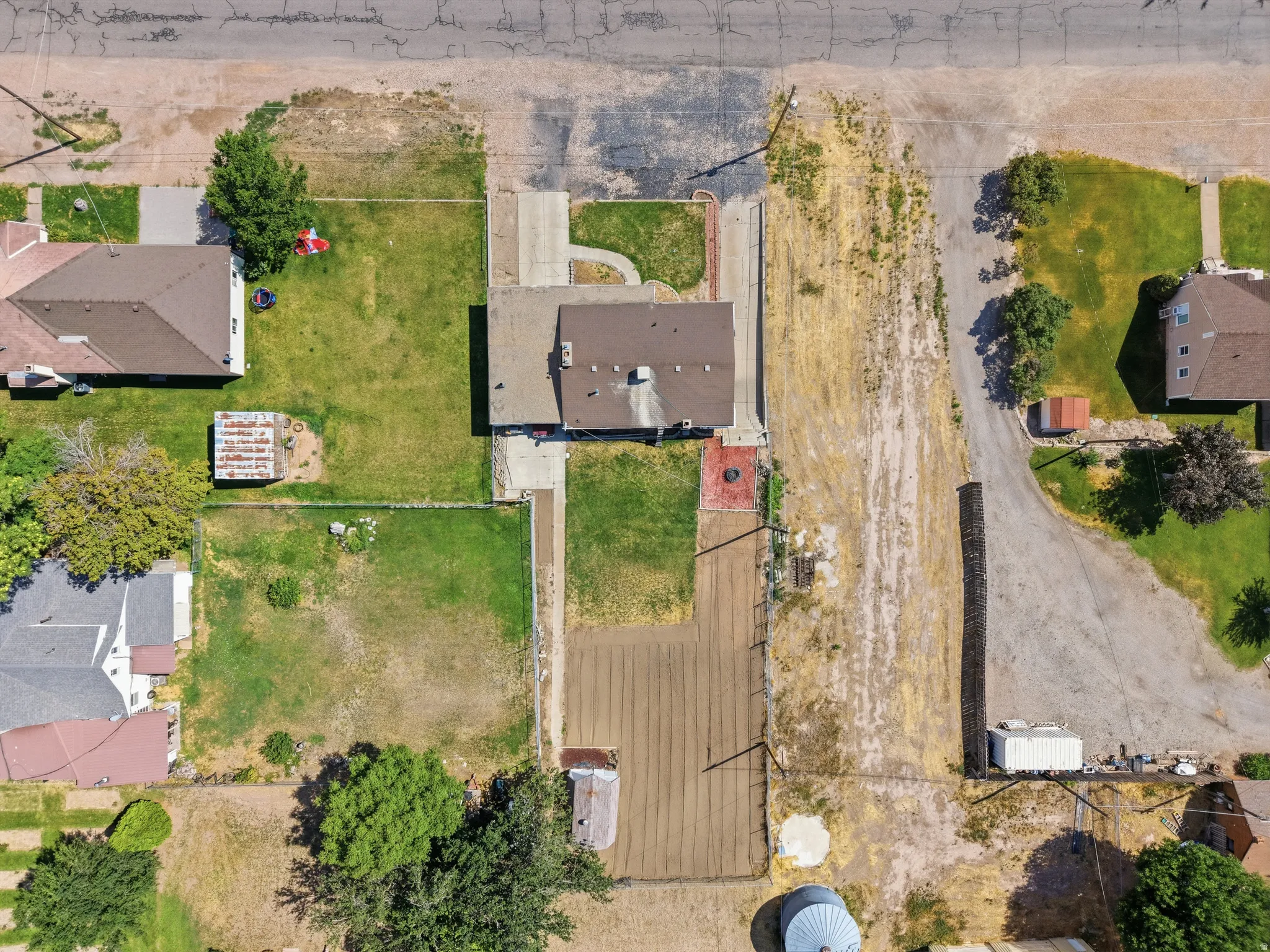 Aerial view of a residential property with a central house featuring a brown shingle roof