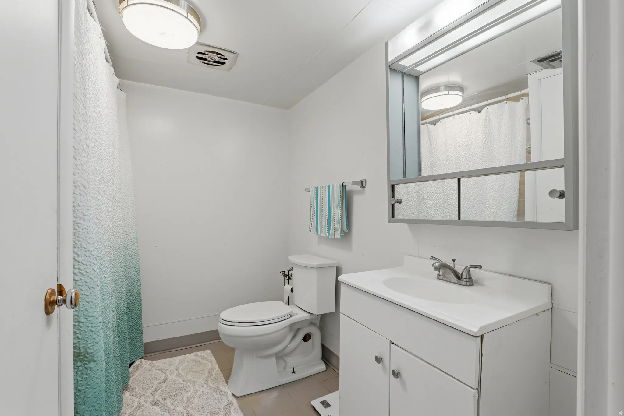 Bathroom featuring a white vanity with integrated sink, a medicine cabinet with mirror, and a toilet