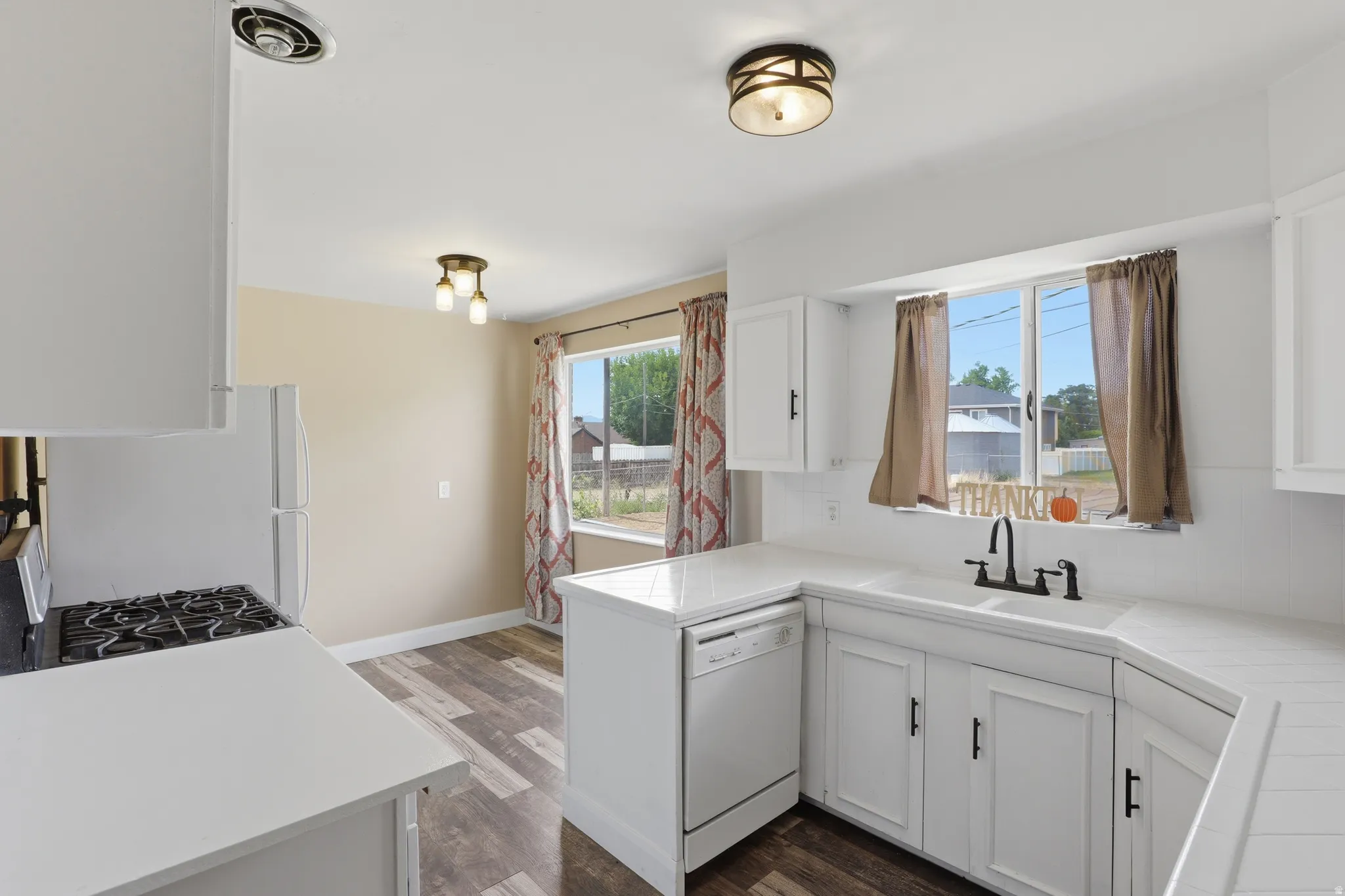 Kitchen featuring white cabinetry, white countertops, a gas range, and wood-finish flooring