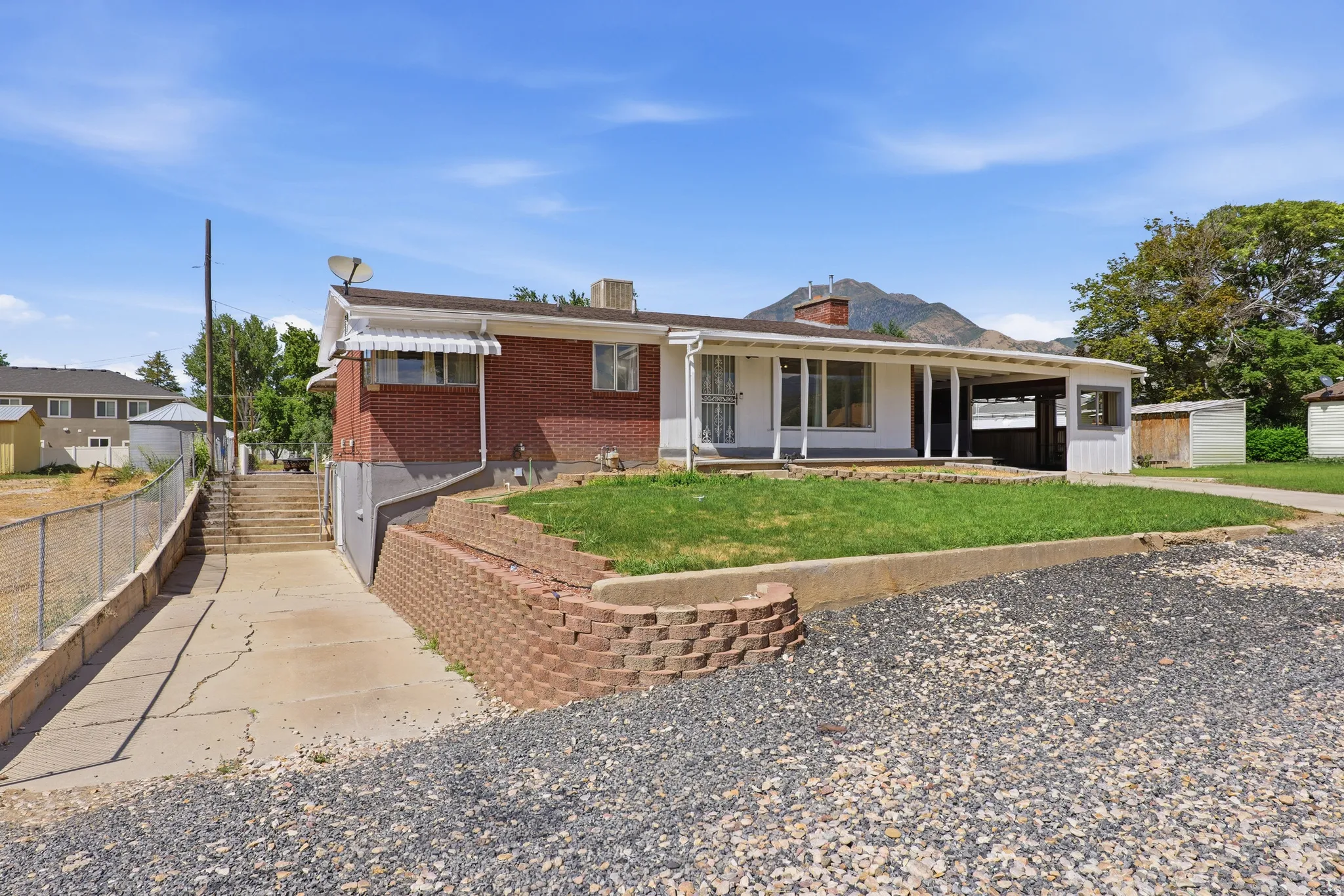 Ranch-style residence featuring a brick facade, covered front porch, and a gravel driveway