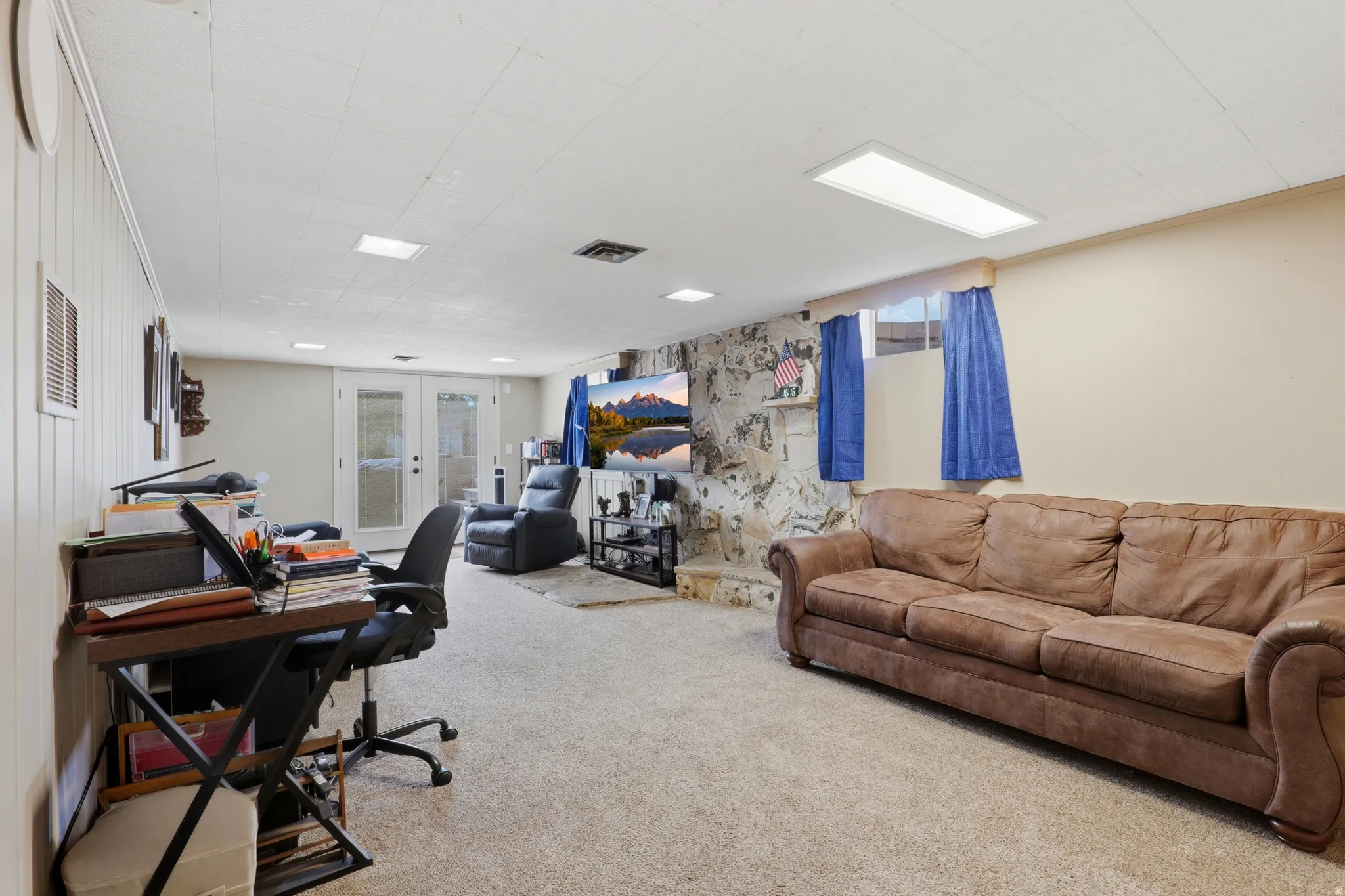 Carpeted interior space featuring a stone-clad fireplace and a built-in recessed display shelf