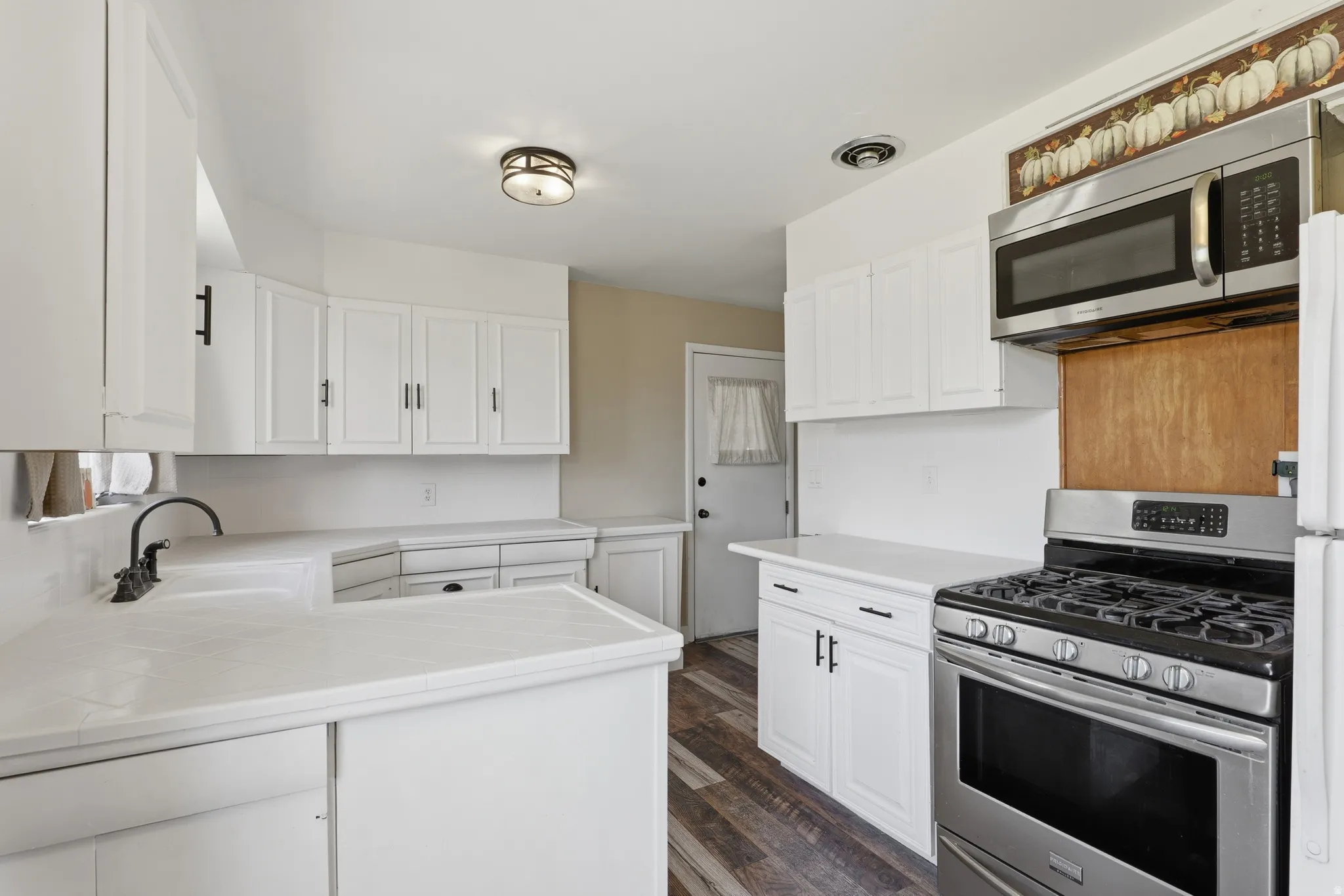 Contemporary kitchen featuring white cabinetry, light-toned countertops, and wood-finish flooring