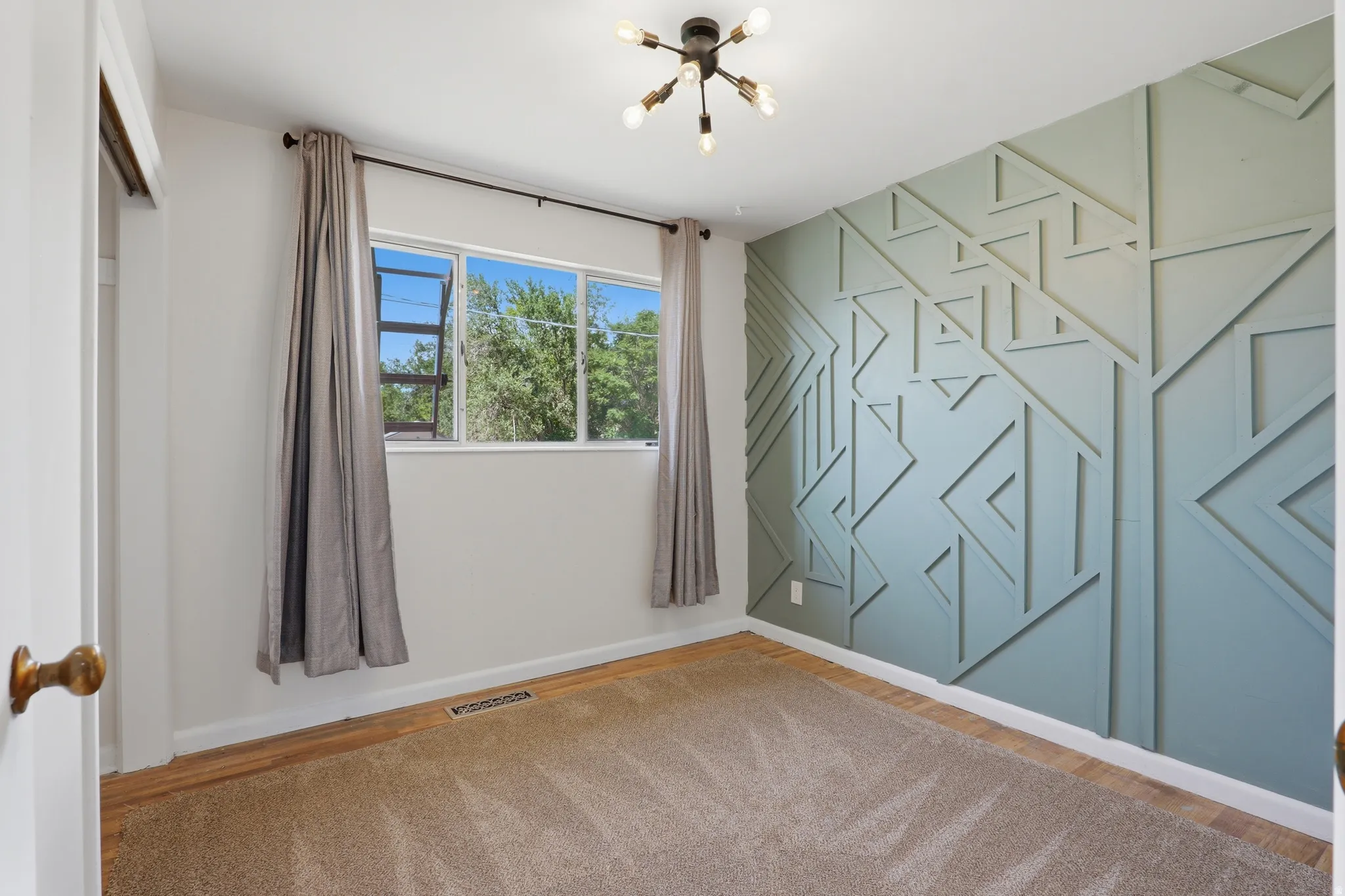 Accent wall featuring geometric paneling, carpet flooring, a multi-pane window, and a modern ceiling light fixture