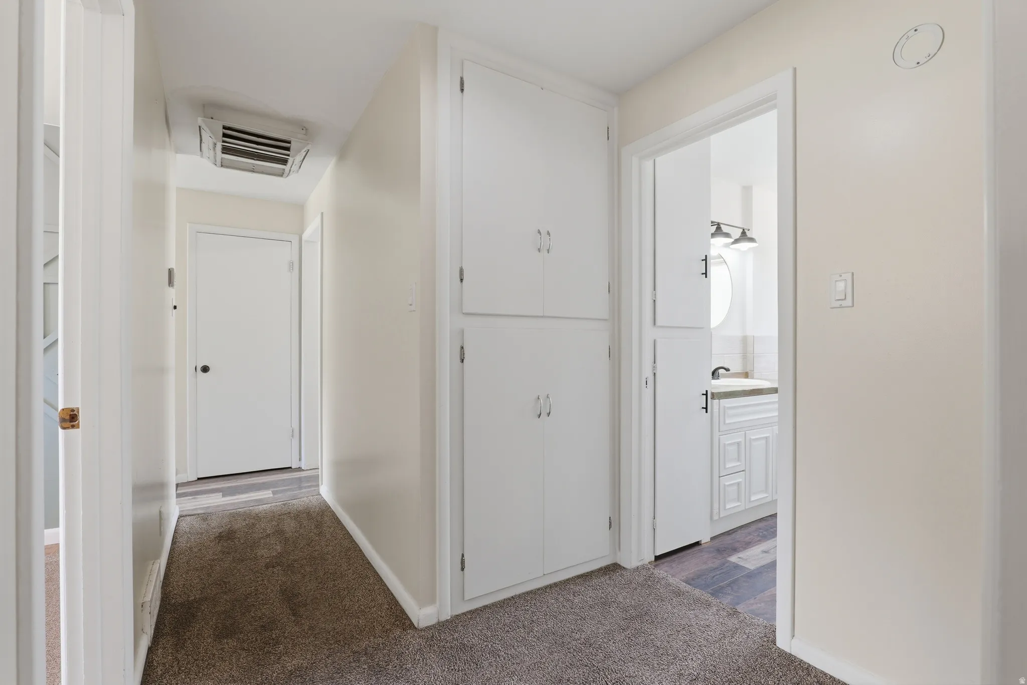 Hallway featuring plush carpeting, built-in white cabinetry, and a white interior door