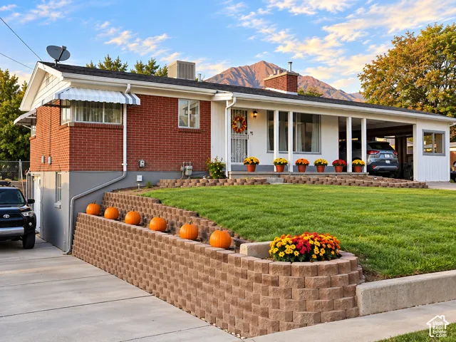 Red brick exterior with white trim, featuring a covered front porch and an attached carport