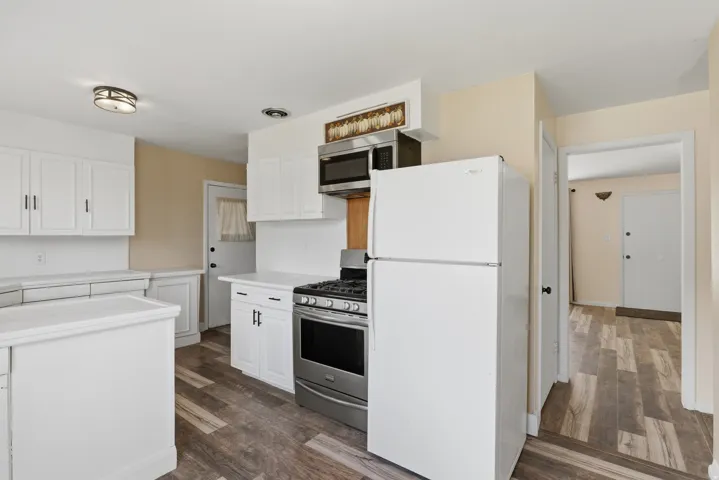 Kitchen featuring wood-finish flooring, white cabinetry, white countertops, and stainless steel appliances