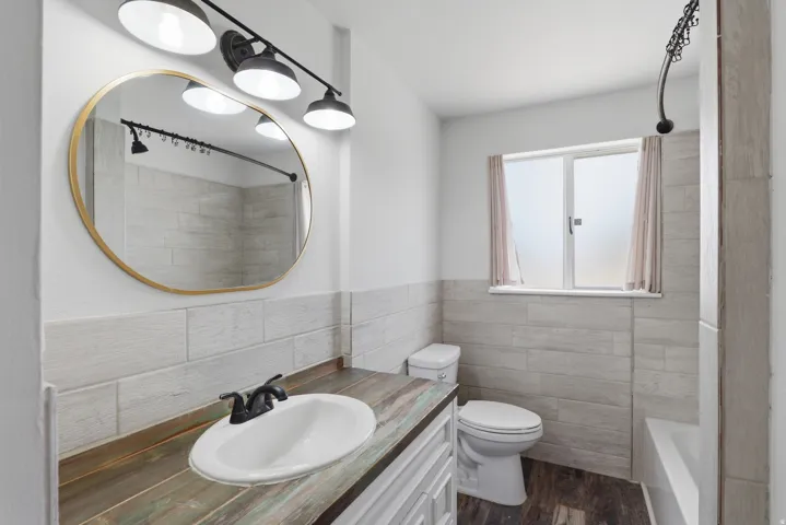 Bathroom vanity featuring a vessel sink with a matte black faucet, a gold-framed oval mirror, and a three-light fixture