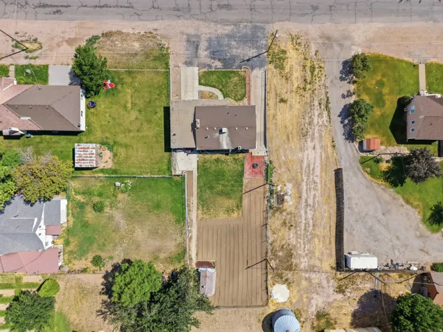 Aerial view of a residential property with a central house featuring a brown shingle roof