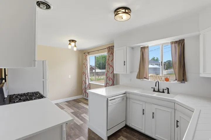 Kitchen featuring white cabinetry, white countertops, a gas range, and wood-finish flooring