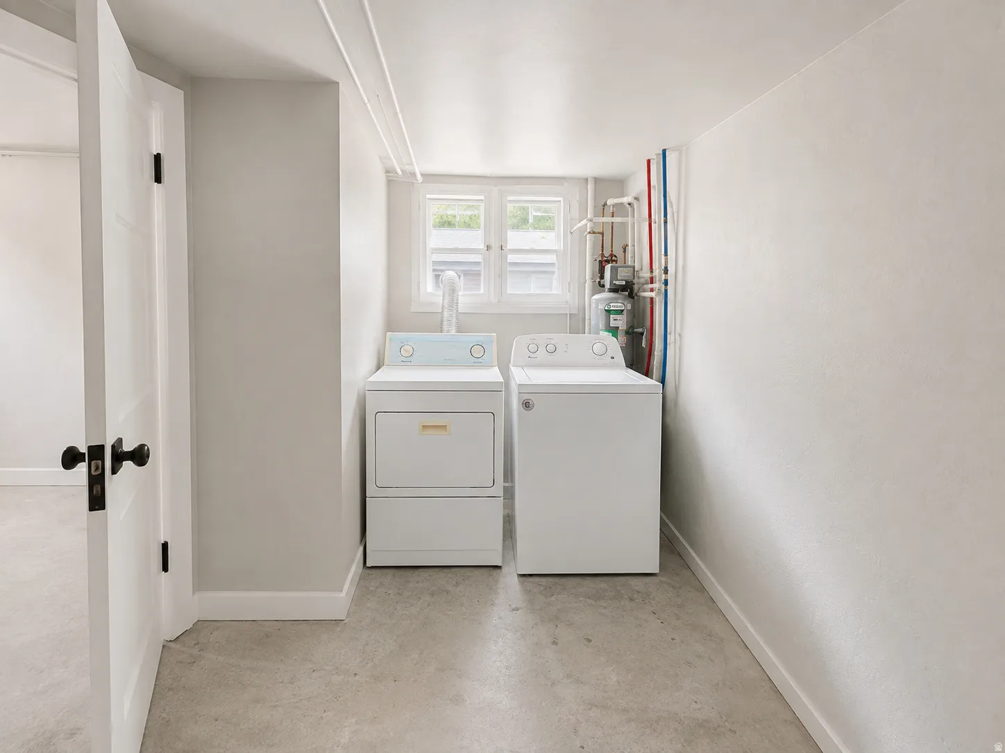 Dedicated laundry area with concrete flooring, a single window, and visible utility connections