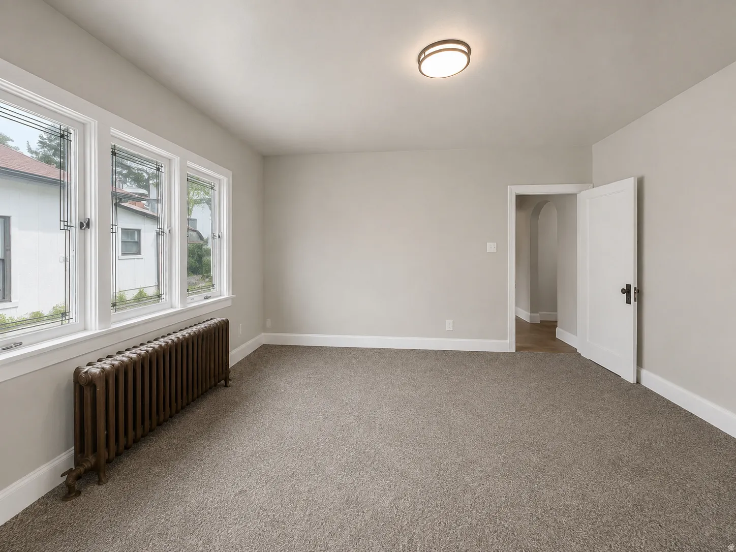 Carpeted room with multiple windows featuring decorative leaded glass, a ceiling-mounted light fixture, and a solid core door