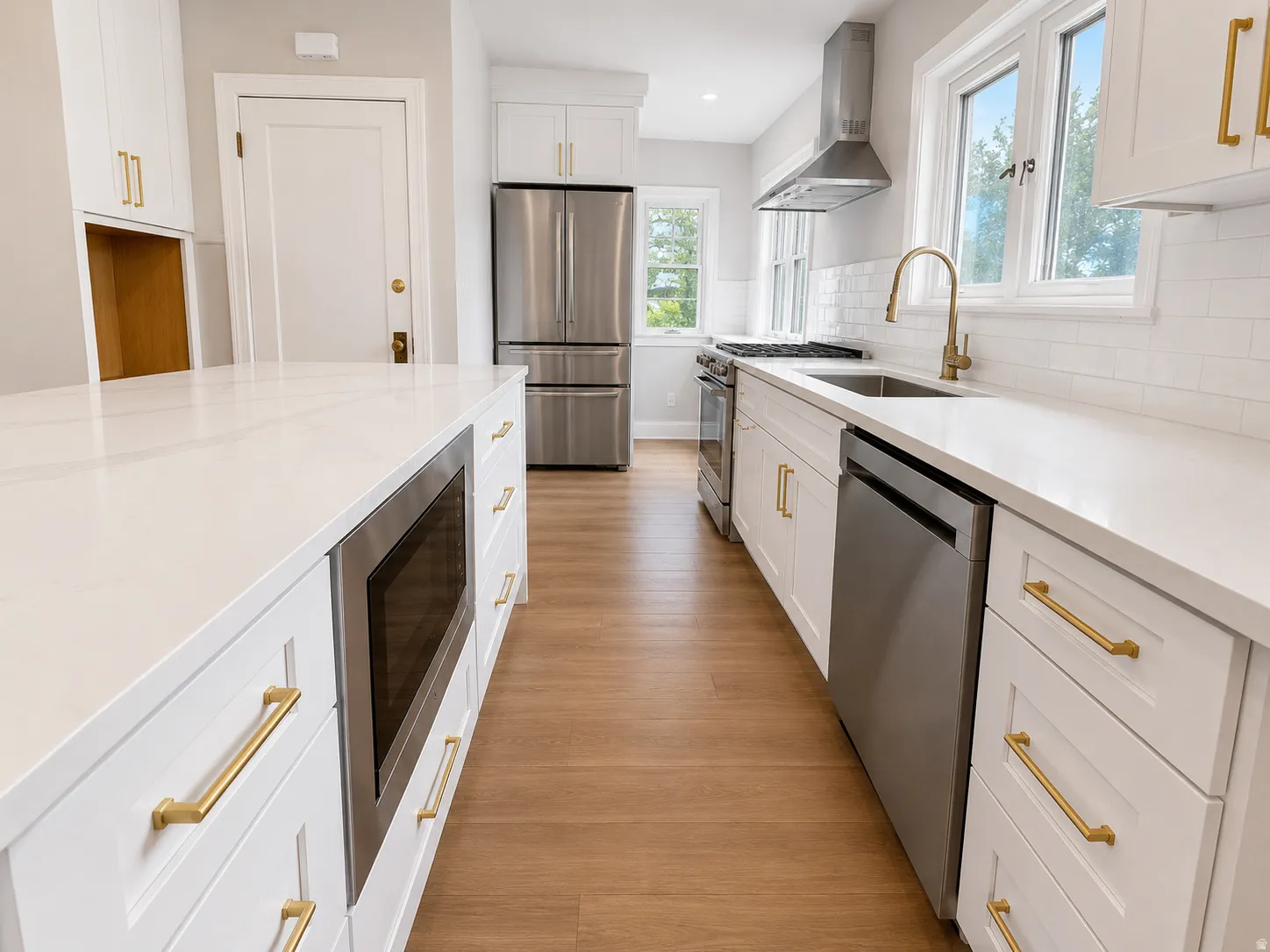 Kitchen featuring white shaker cabinetry, stainless steel appliances, light-toned wood-finish flooring, white subway tile backsplash, and white countertops