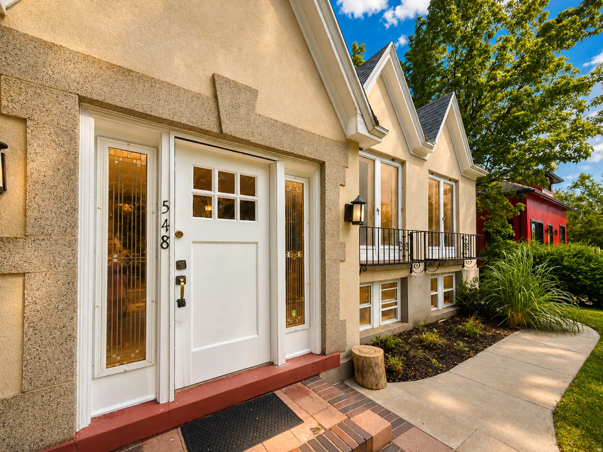 Stucco exterior with stone trim, multi-pane front door, and sidelights