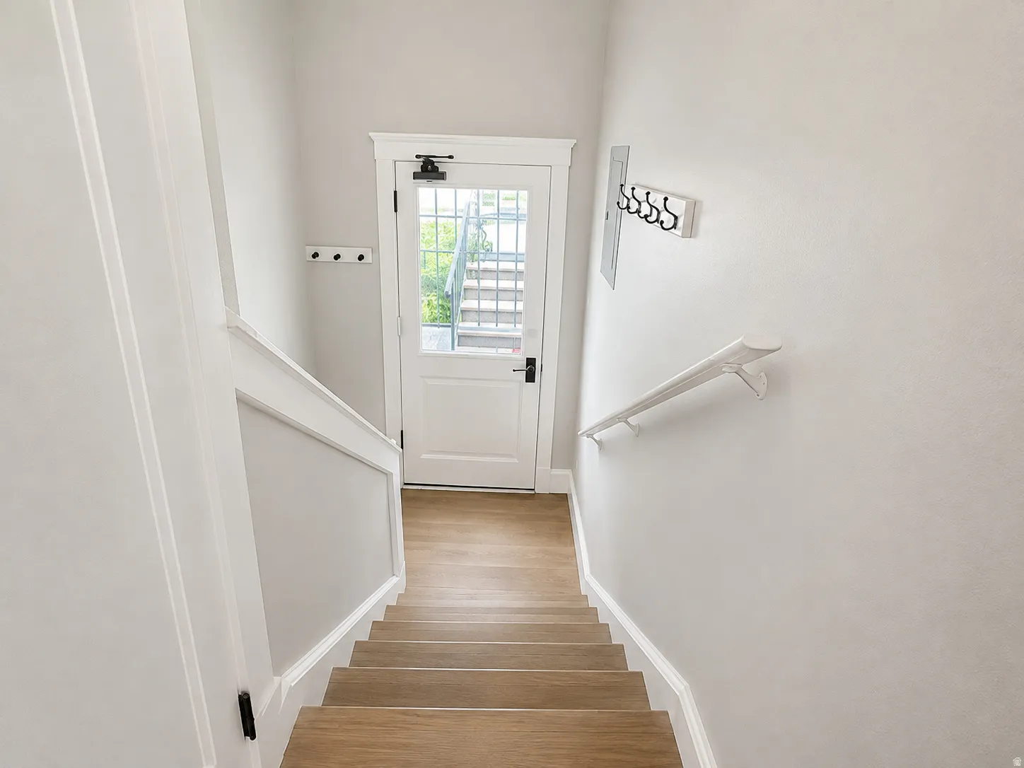 Staircase featuring wood-finish treads, white painted risers, and a white handrail