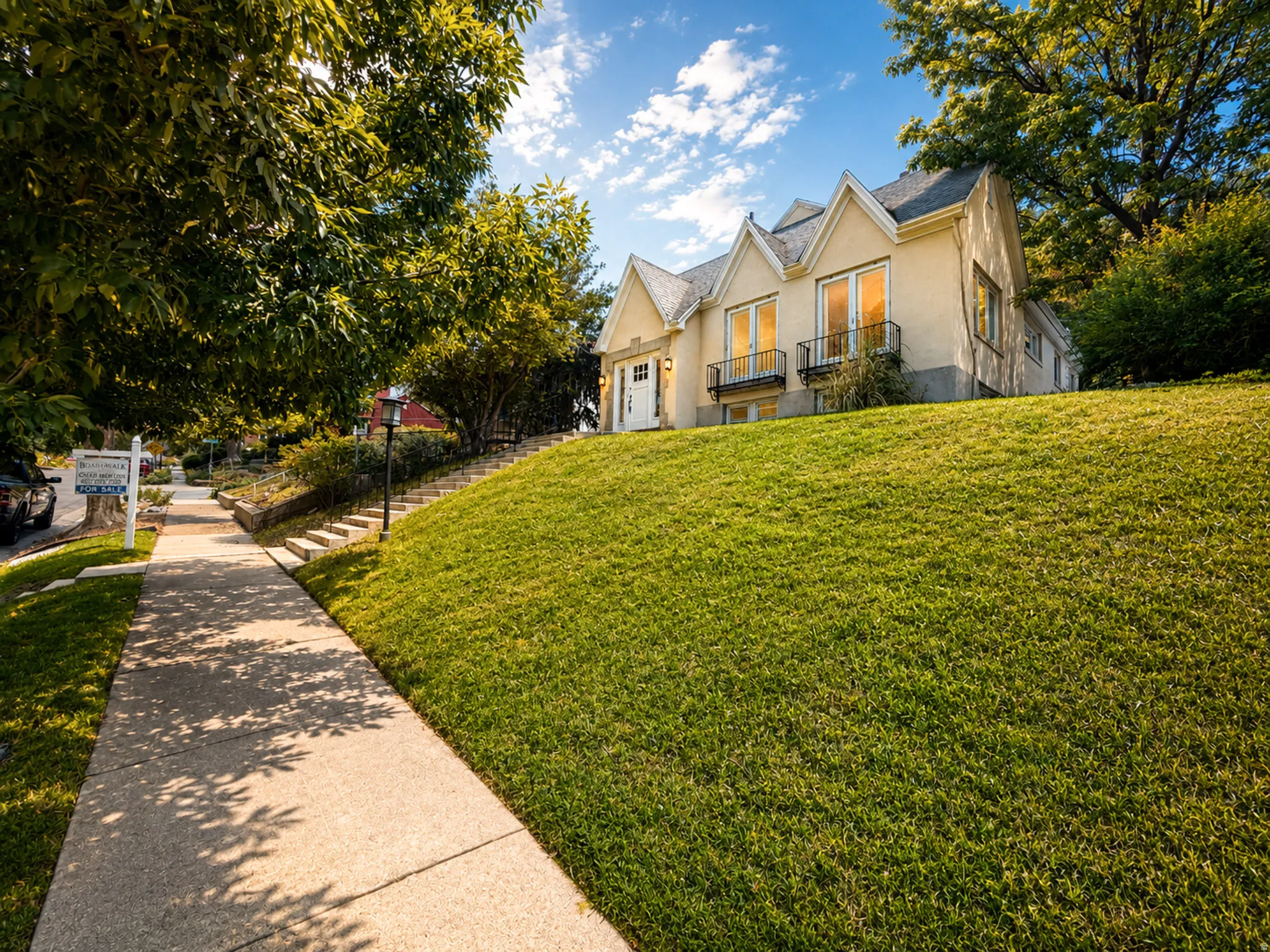 Exterior featuring a stucco finish, multiple gabled rooflines, and a spacious green lawn