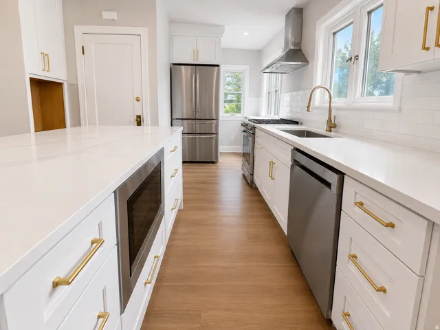 Kitchen featuring white shaker cabinetry, stainless steel appliances, light-toned wood-finish flooring, white subway tile backsplash, and white countertops