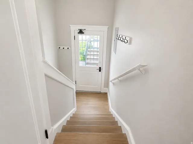 Staircase featuring wood-finish treads, white painted risers, and a white handrail