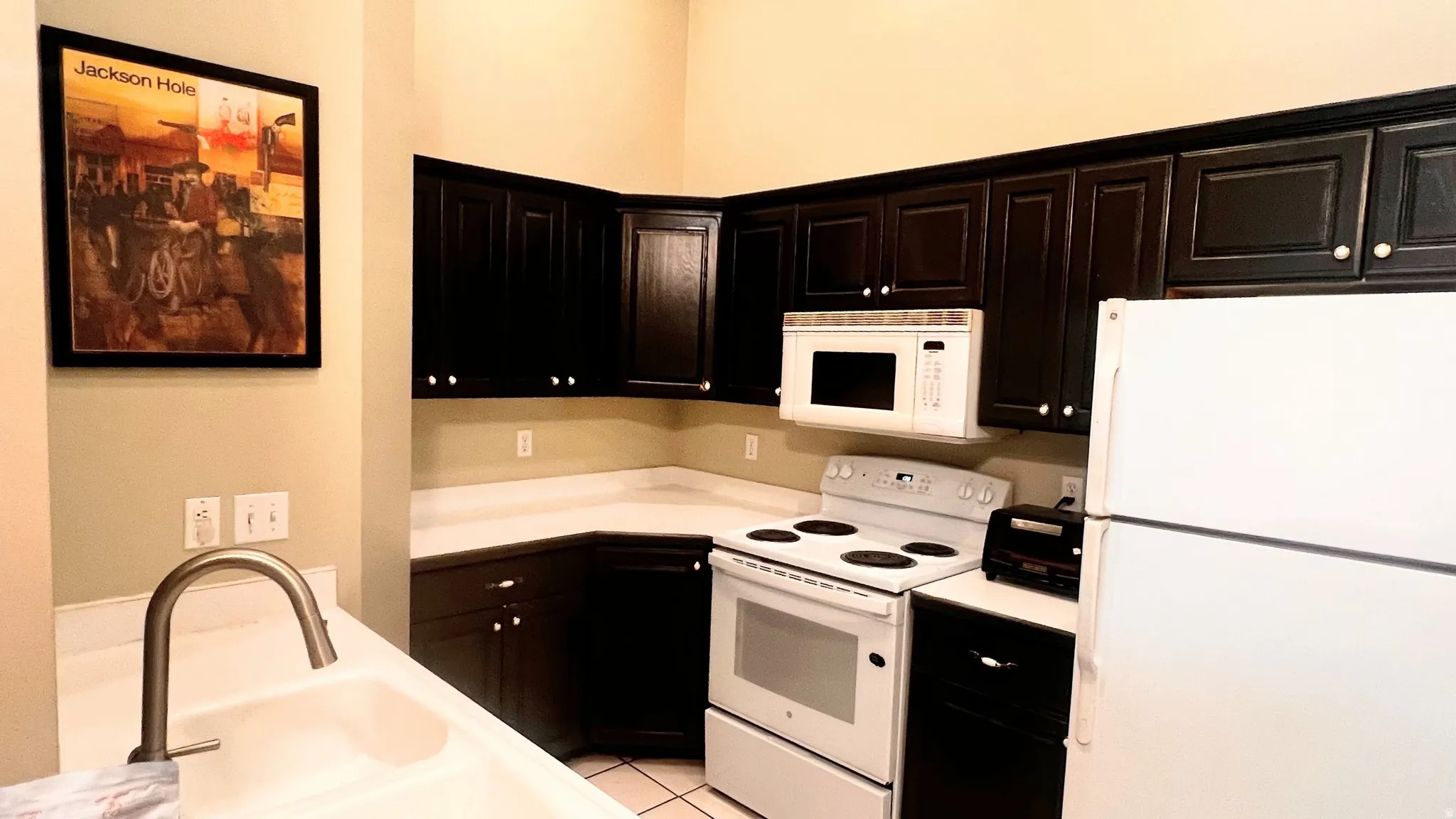 Kitchen featuring dark wood-finish cabinetry, white countertops, built-in microwave, white electric range, and a white refrigerator
