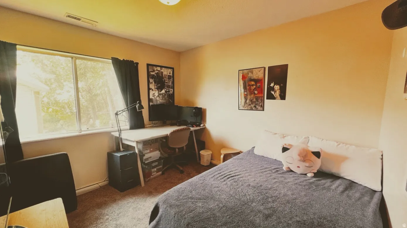 Bedroom featuring a large window, light-colored walls, and carpeting