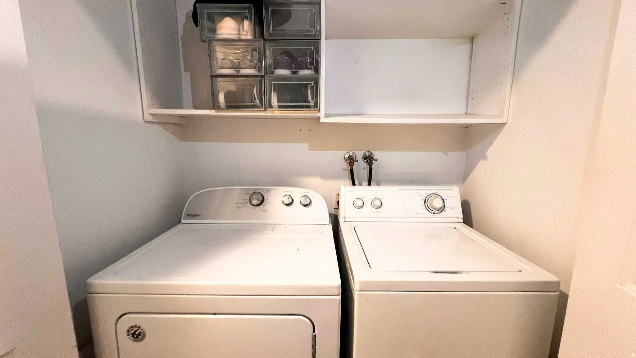 Dedicated laundry area with white appliances and wall-mounted shelving for organization