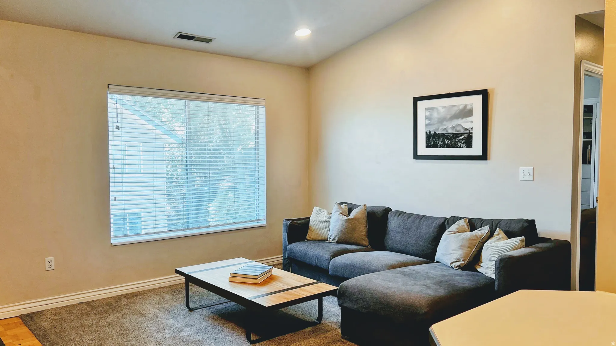 Living area featuring a vaulted ceiling, recessed lighting, and a large window with horizontal blinds