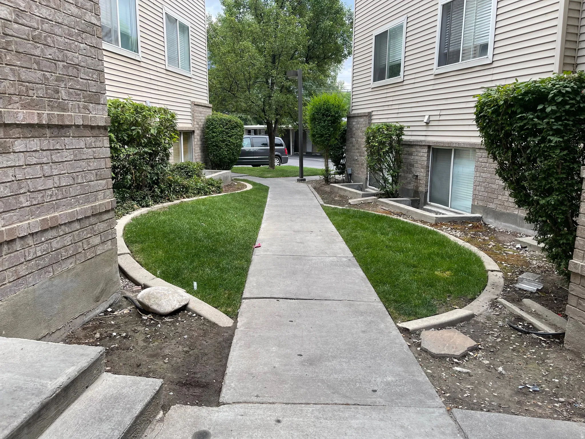 Concrete walkway flanked by manicured green lawn and established perimeter plantings