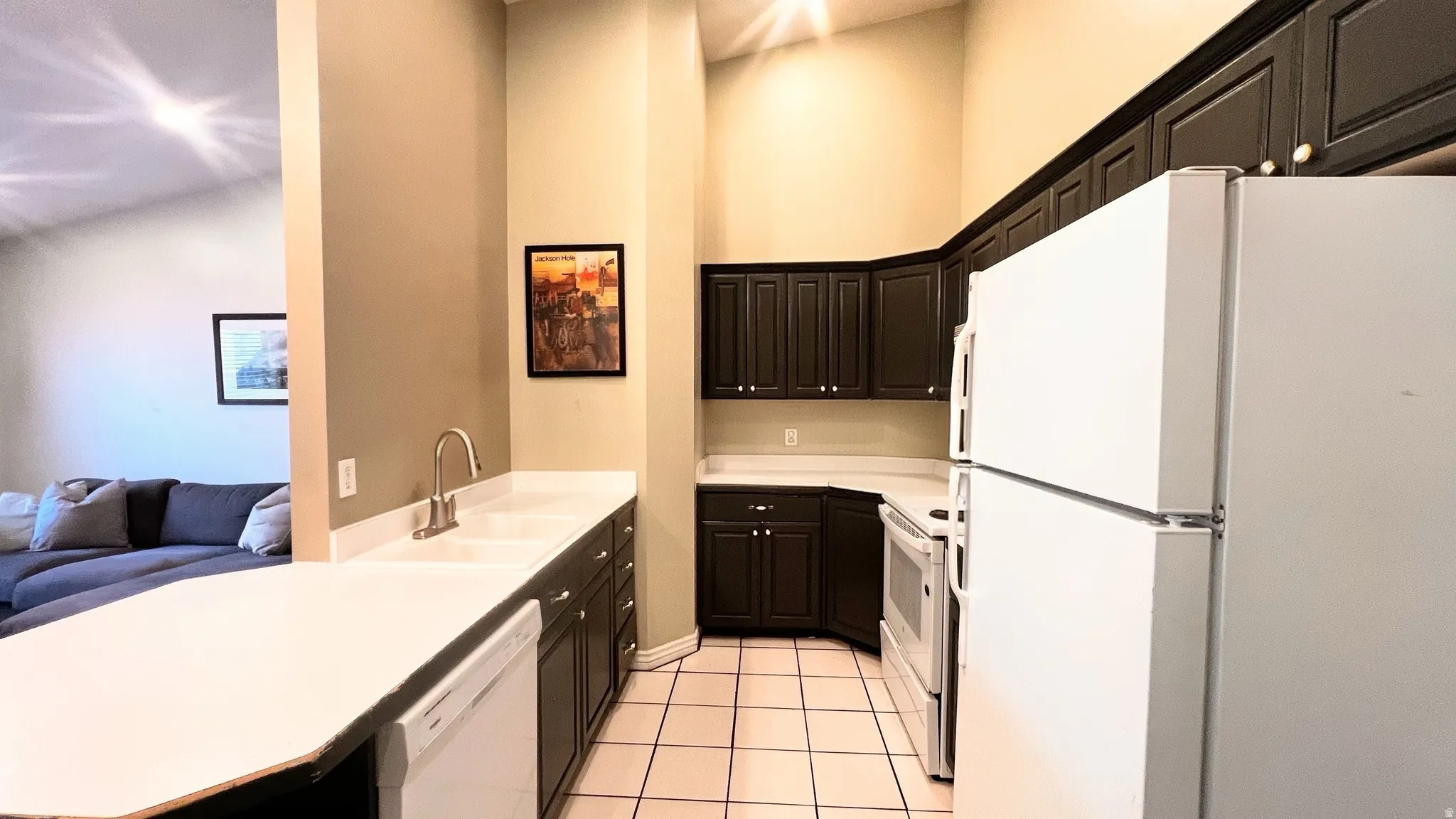Kitchen featuring dark cabinetry, light countertops, and white appliances