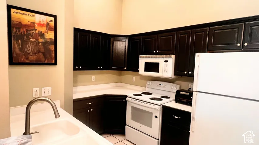 Kitchen featuring dark wood-finish cabinetry, white countertops, built-in microwave, white electric range, and a white refrigerator