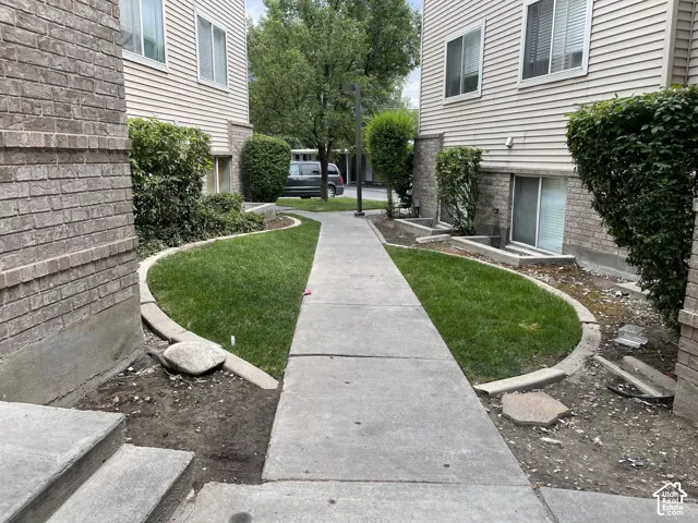 Concrete walkway flanked by manicured green lawn and established perimeter plantings