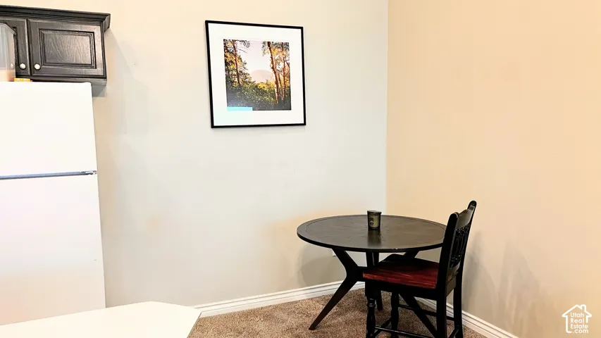Kitchenette featuring white refrigerator, dark wood cabinetry, and neutral wall paint