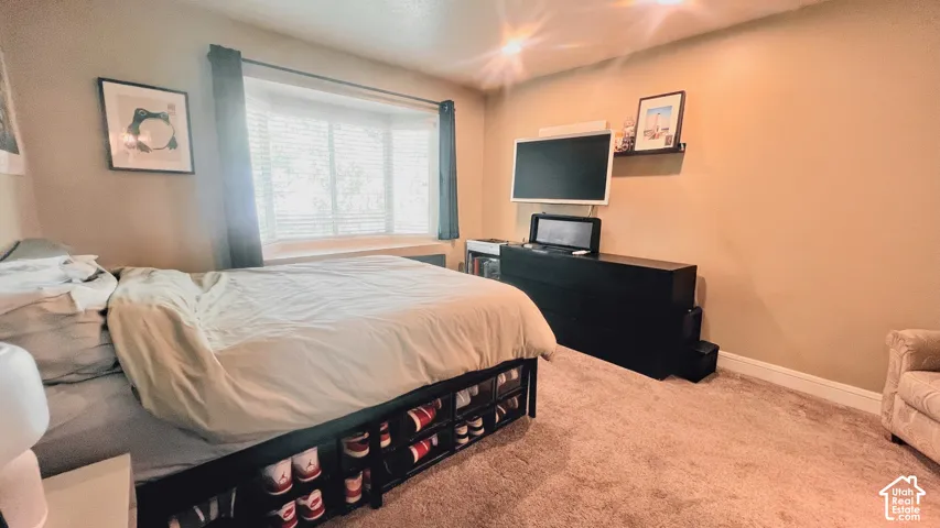 Primary bedroom, Bay window with blinds, light tan walls, and carpet flooring