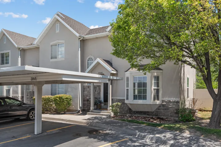 Multi-story exterior featuring a bay window, stone veneer accents, and a covered carport