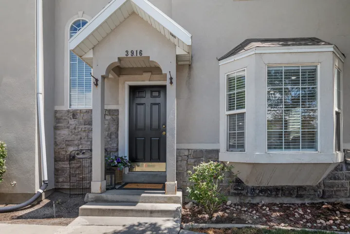 Exterior featuring a covered entryway, decorative stone facade, and a multi-pane bay window
