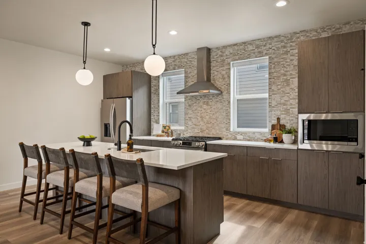 Contemporary kitchen featuring a large island with white countertops, stainless steel appliances, and wood-finish flooring
