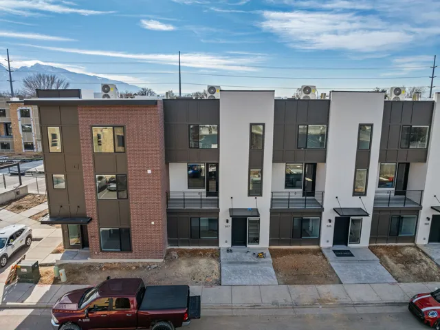 Contemporary townhomes featuring a multi-textured facade with brick, dark paneling, and white stucco