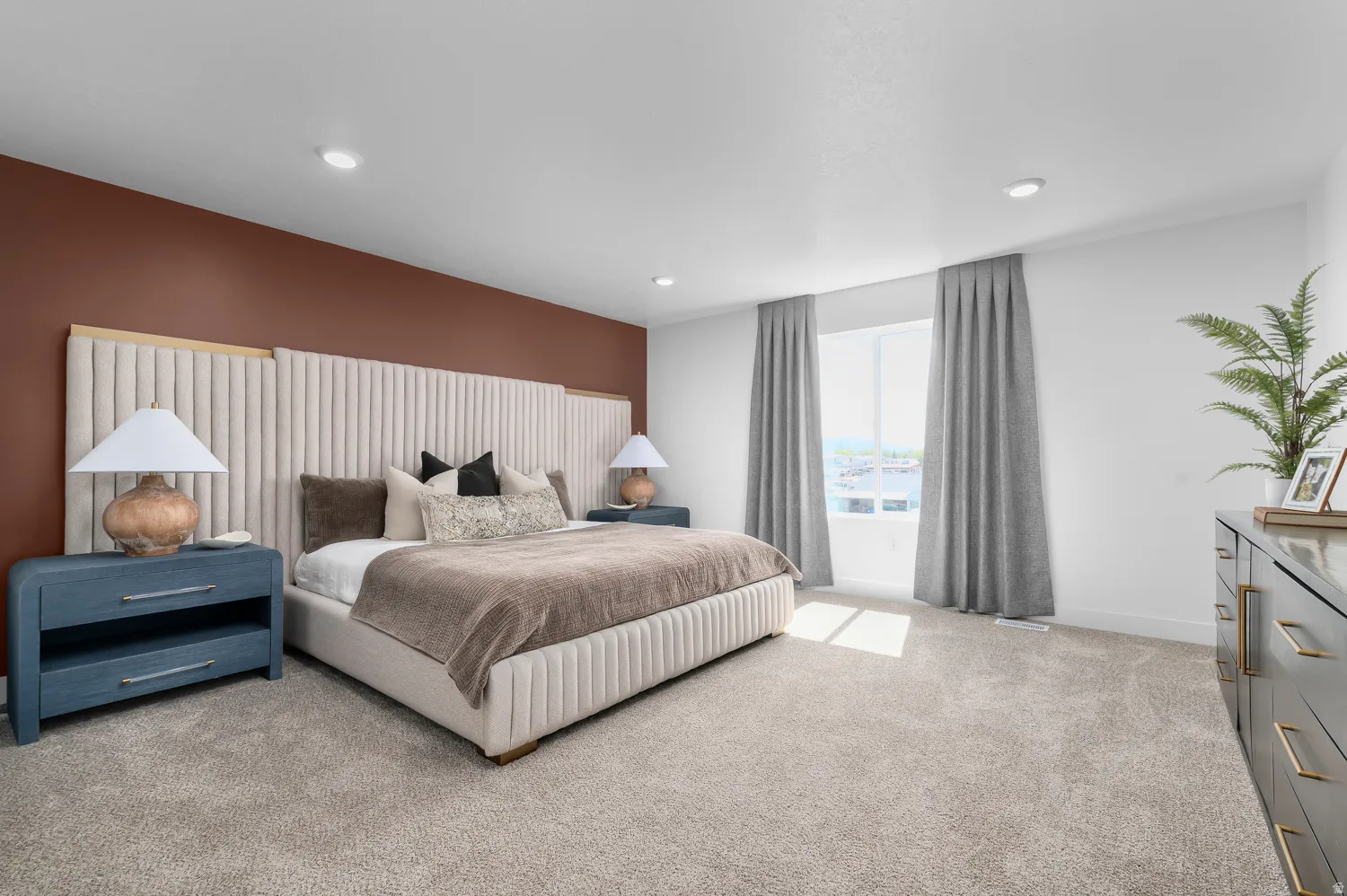 Spacious bedroom featuring neutral carpeting, a large picture window, and recessed lighting